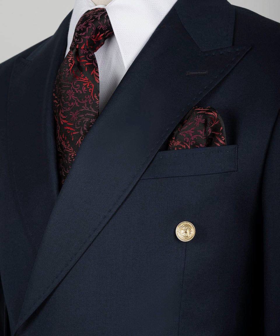 Navy suit jacket with a red patterned tie and pocket square on a gray background
